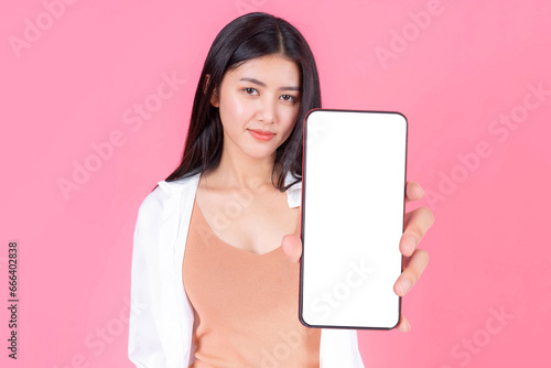 beautiful Asian young woman  showing smart phone with blank screen , white screen for Mobile App Advertising isolated on pink background