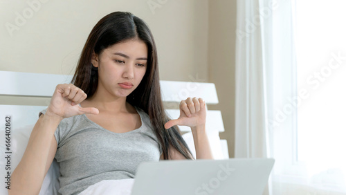 Young woman sitting and use laptop in bedroom with upset