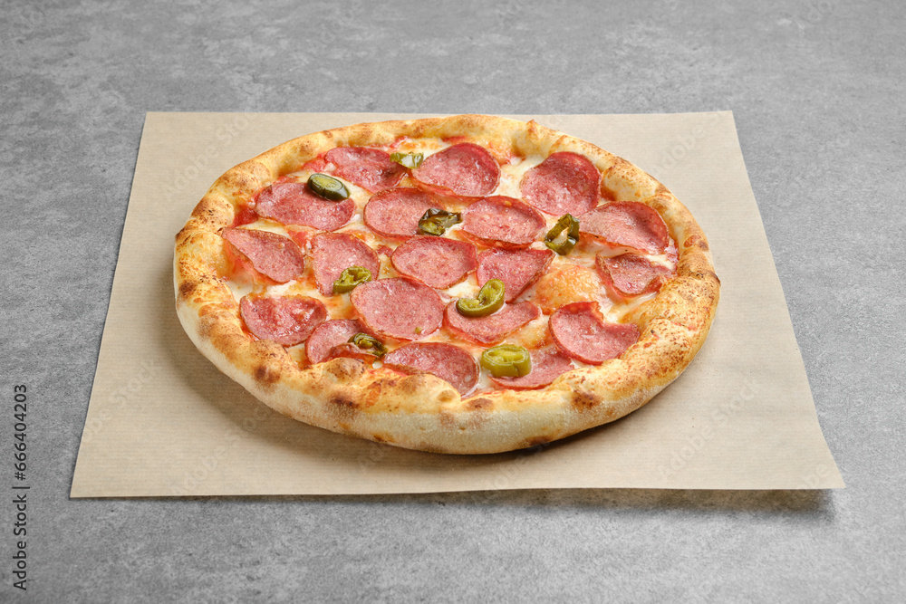 Spicy pizza with sausage and jalapeno pepper on parchment Spicy pizza with sausage and jalapeno pepper on parchment