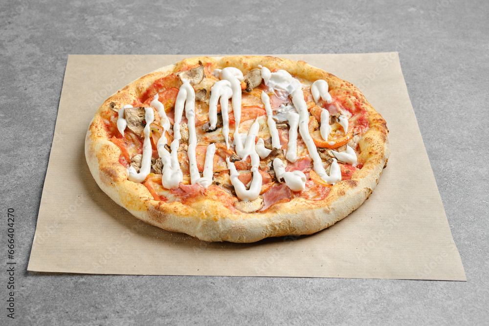 Pizza with ham, champignon and tomato slices on parchment paper Pizza with ham, champignon and tomato slices on parchment paper