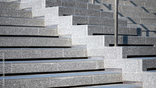 Outdoor concrete stair covered with rough granite tiles. Step of exterior stairway with stainless steel railing. Modern staircase design. Architectural element detail photo
