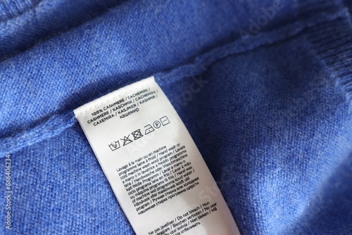 Clothing label in different languages on blue garment, closeup