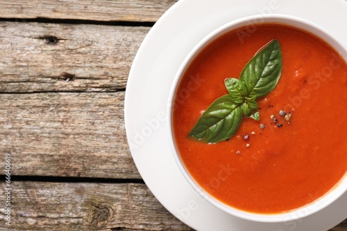 Delicious tomato soup with basil and spices on wooden table, top view. Space for text