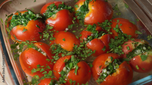 Stuffed pickled tomatoes lie in glass container.