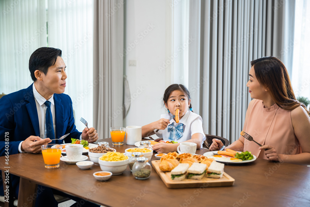 Asian family father, mother with children daughter eating healthy breakfast food on dining table kitchen in mornings together at home before father left for work, happy couple adult family concept Asian family father, mother with children daughter eating healthy breakfast food on dining table kitchen in mornings together at home before father left for work, happy couple adult family concept