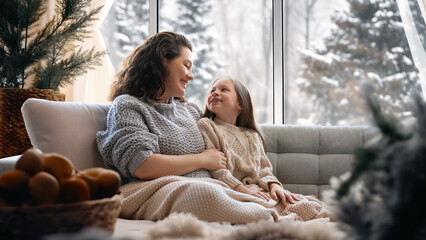 Mother and daughter enjoying winter nature in the  window