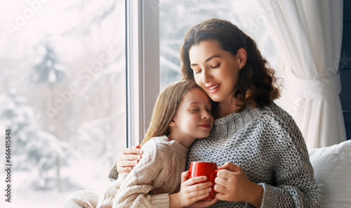 Mother and daughter enjoying winter nature in the  window