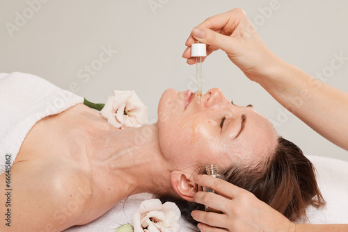 Close-up of the process of a beautician applying oil to a woman's face with a pipette Facial skin care with medicated cosmetic oil. hold professional cure serum bottle oil treatment cosmetologist