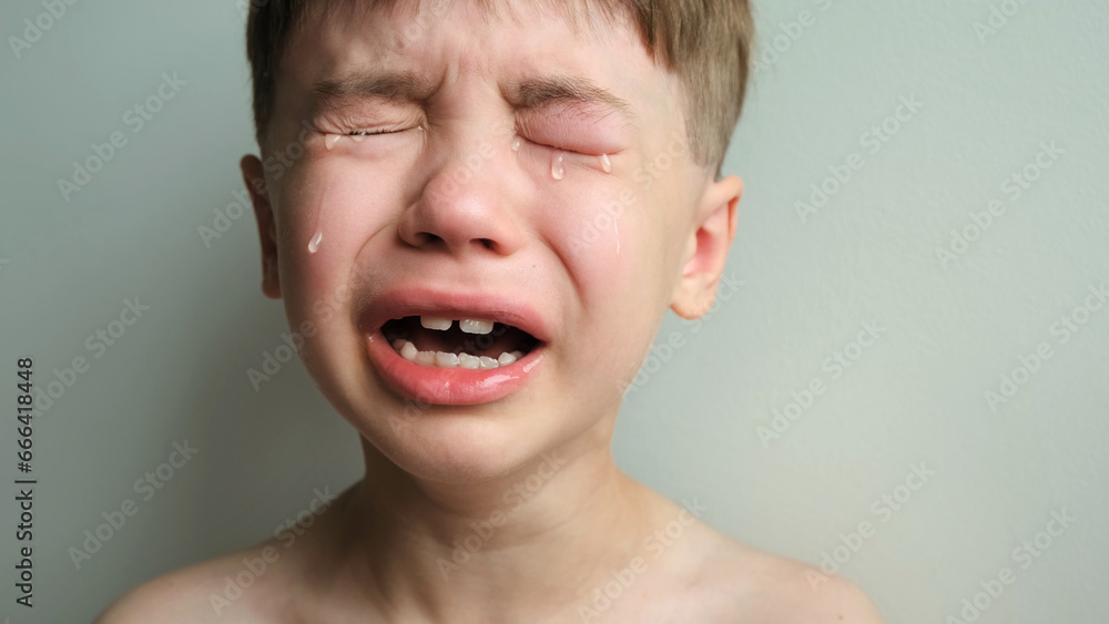 Dramatic portrait of a crying 7 year old boy. Tears flow from the eyes