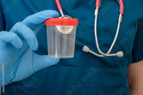 Badanie moczu, lekarz trzyma w dłoniach pusty pojemnik na mocz