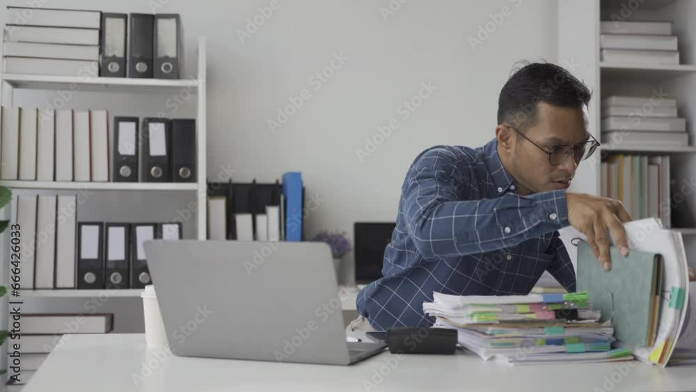 Stressed Asian businessman working with financial documents and stressed about work Tired employees are overloaded in the office.