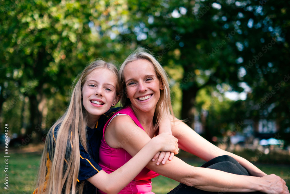 Smiling daughter with arm around mother sitting in park Smiling daughter with arm around mother sitting in park