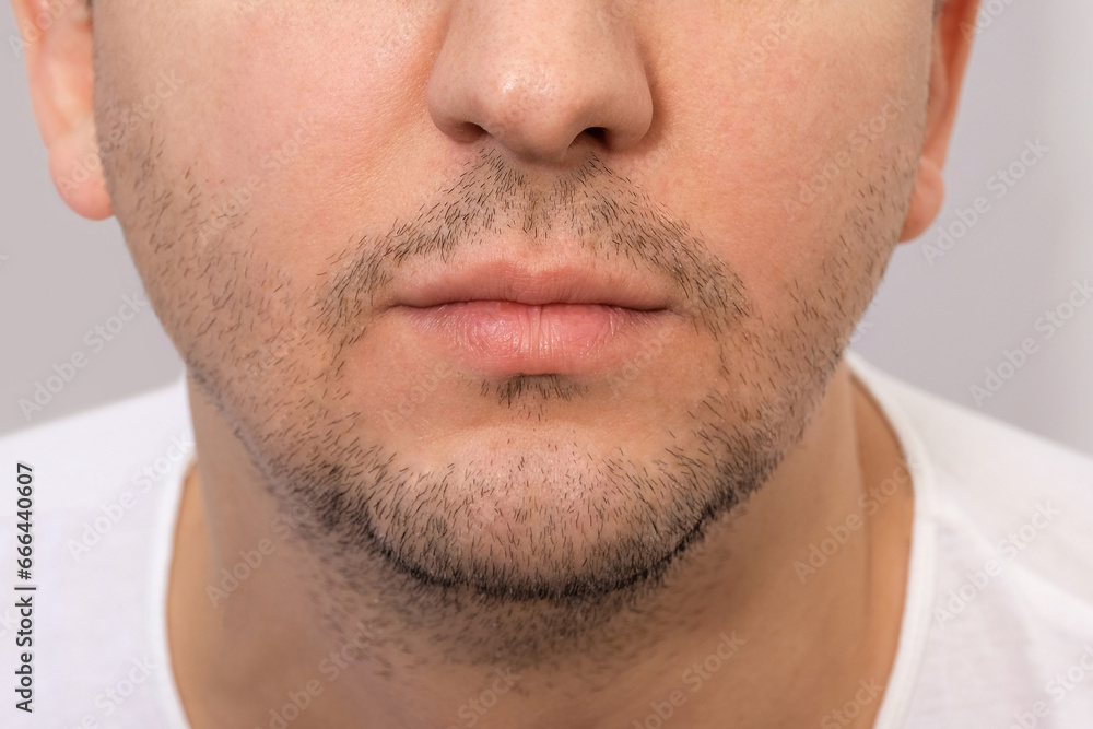 Close-up of the face of a young man with a beard. Young bearded man on a gray background.