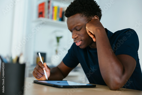Young student studying and writing on tablet PC at desk photo