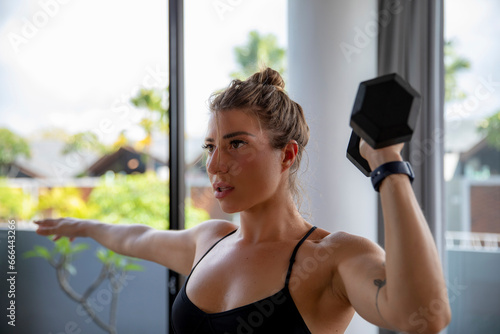 Fit woman exercising with dumbbell at home photo