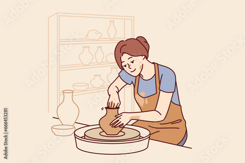 Woman sits in pottery workshop and sculpts jug from clay to sell handmade souvenirs in craft goods shop. Girl craftsman is interested in pottery art, dressed in apron stained with dirt.