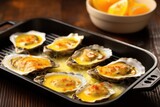 oysters on grill pan, small dish of golden garlic sauce