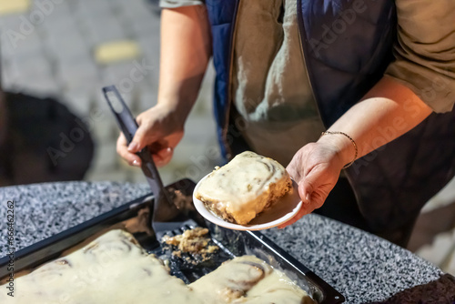 A woman puts cinnabon on a plate at a family party.