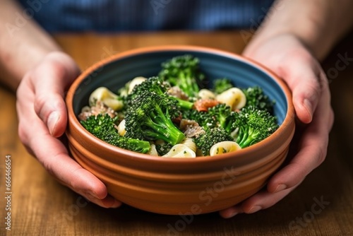 hand holding a bowl of orecchiette with broccoli rabe