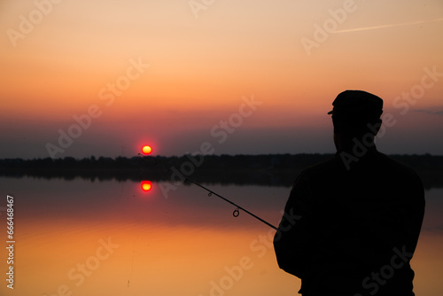 A man is fishing on the lake at sunset. High quality photo