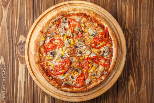 delicious pizza with chicken, mushrooms, cheese, tomatoes and corn on a wooden background