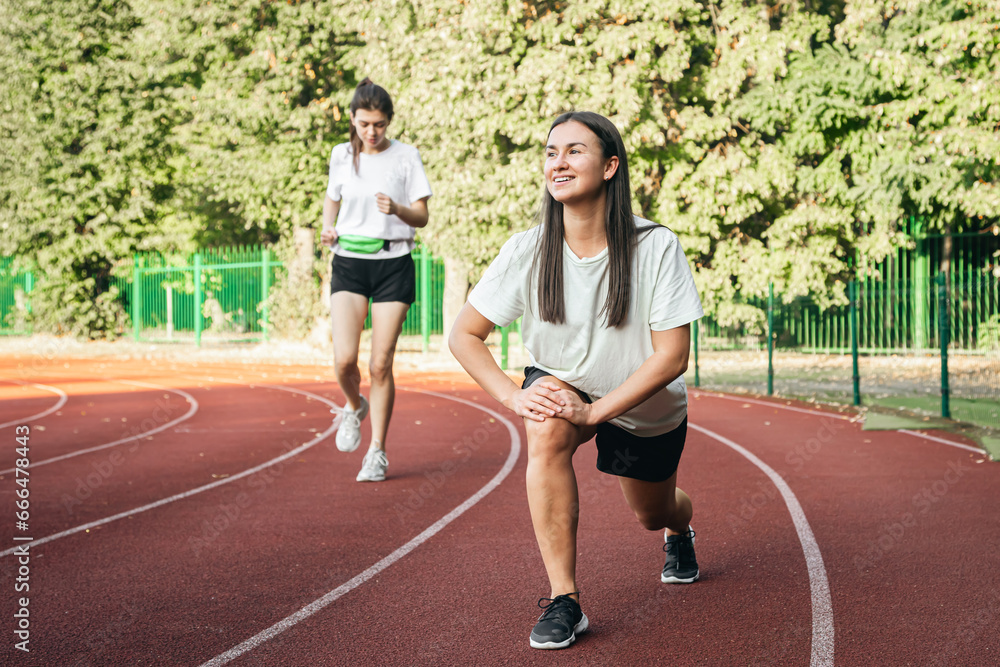 Obraz premium A young woman runner in start position on running track while work out.