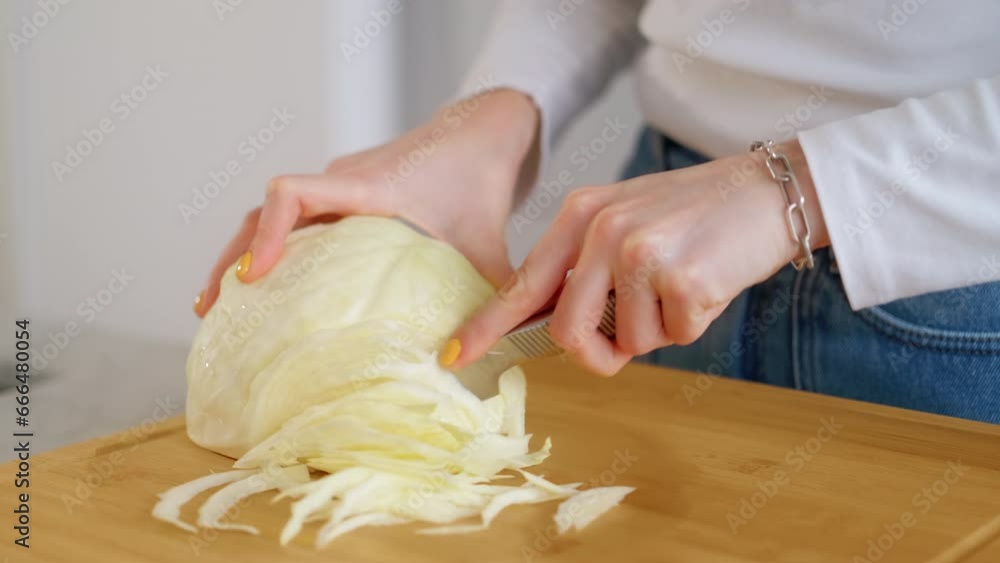 Young woman hands cutting cabbage head with sharp knife on wooden chopping board on table in domestic kitchen. Natural organic soup ingredient. Preparing vegetables for vegetarian dish. Food Delivery Young woman hands cutting cabbage head with sharp knife on wooden chopping board on table in domestic kitchen. Natural organic soup ingredient. Preparing vegetables for vegetarian dish. Food Delivery