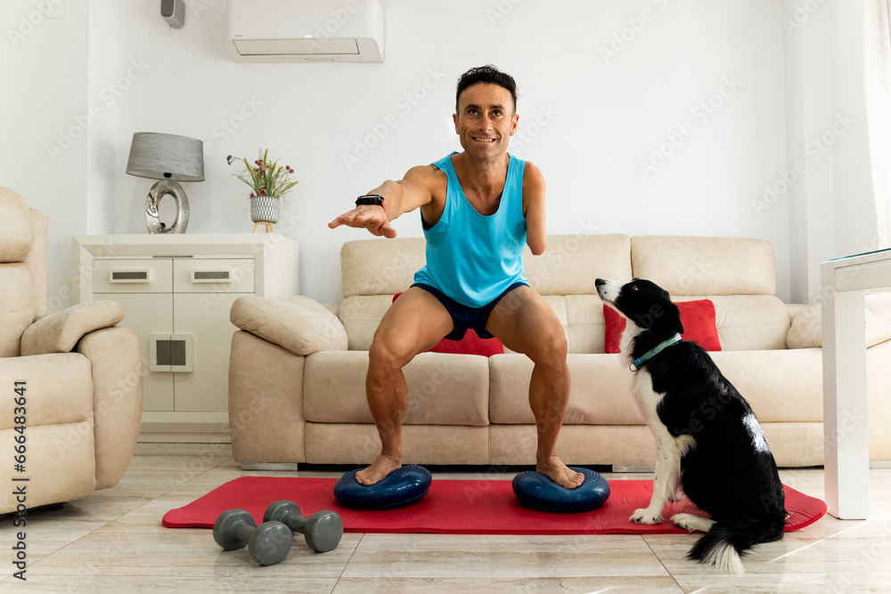 An adult man with an amputated arm exercises in his living room with