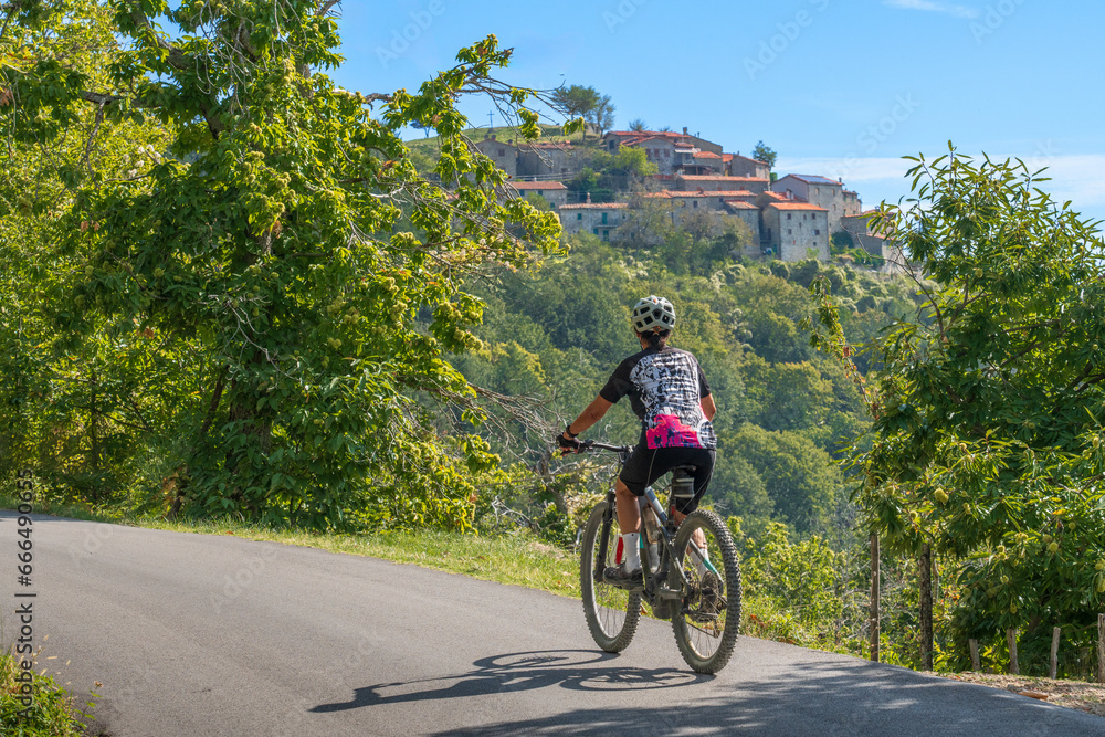 nice senior woman riding her electric mountain bike in the Pratomagno mountains below village of Anciolina in Tuscany,Italy