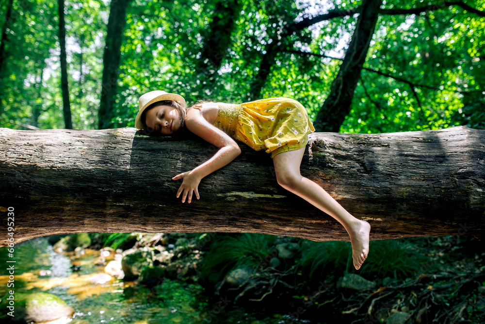 Preteen girl lying on tree trunk in nature Stock Photo | Adobe Stock