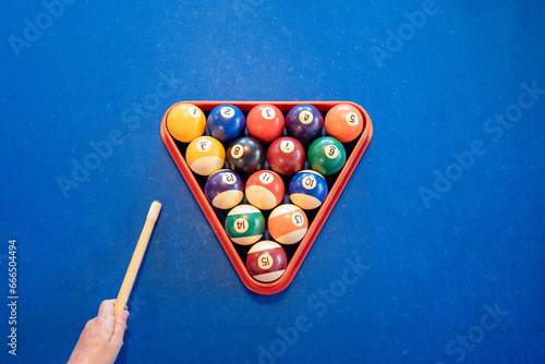 Billiard balls on pool table near anonymous person holding cue photo