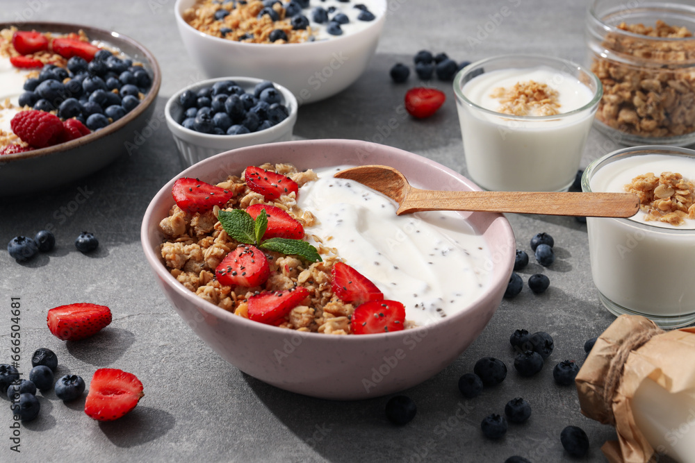 Bowls with yogurt and berries, wooden spoon and milk bottle on gray background Bowls with yogurt and berries, wooden spoon and milk bottle on gray background