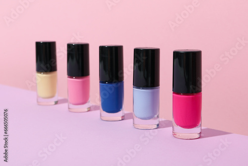 Multicolored nail polishes on a pink background © Atlas
