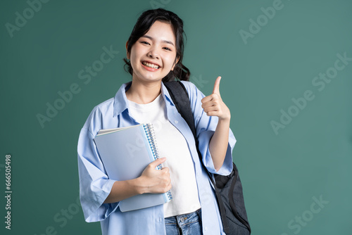 Tableau sur toile Portrait of a beautiful Asian student on a green background
