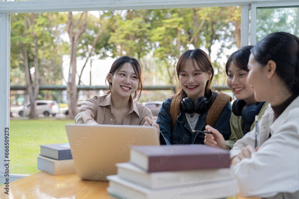 University students sitting together at table with book and laptop. Happy young people doing group study in college campus University students sitting together at table with book and laptop. Happy young people doing group study in college campus