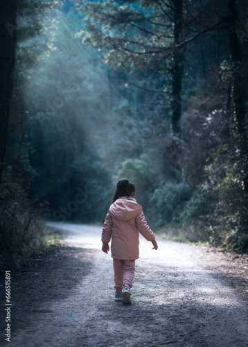 Niña caminando por un camino con los rayos de luz