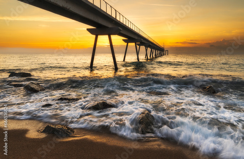 Amanecer en un puente en el mar de Badalona