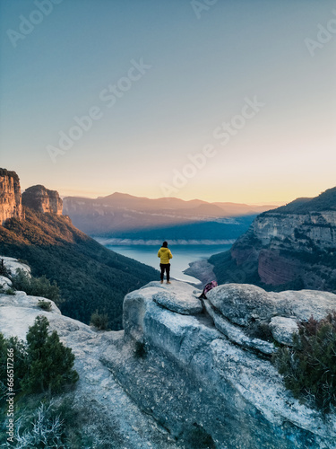 Persona en la alto de un acantilado disfrutando de un atardecer con vistas a un pantano