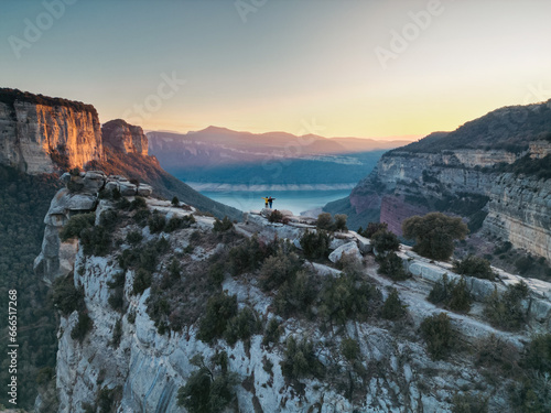 Pareja en lo alto de un acantilado con vistas a un pantano al atardecer.