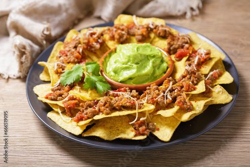 Plate of mexican nachos chips with cheese, meat and guacamole