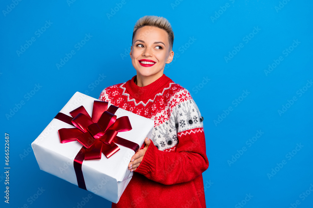 Photo of pretty gorgeous girl with short hairstyle dressed red sweater hold gift box look empty space isolated on blue color background Photo of pretty gorgeous girl with short hairstyle dressed red sweater hold gift box look empty space isolated on blue color background