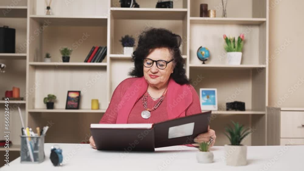 old woman looks through a printed photo album with a smile and good memories old woman looks through a printed photo album with a smile and good memories