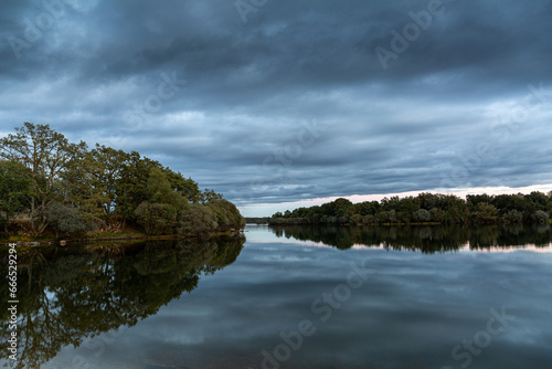Valparaíso reservoir and forests at sunset with reflections and grayish clouds. Zamora, Spain.