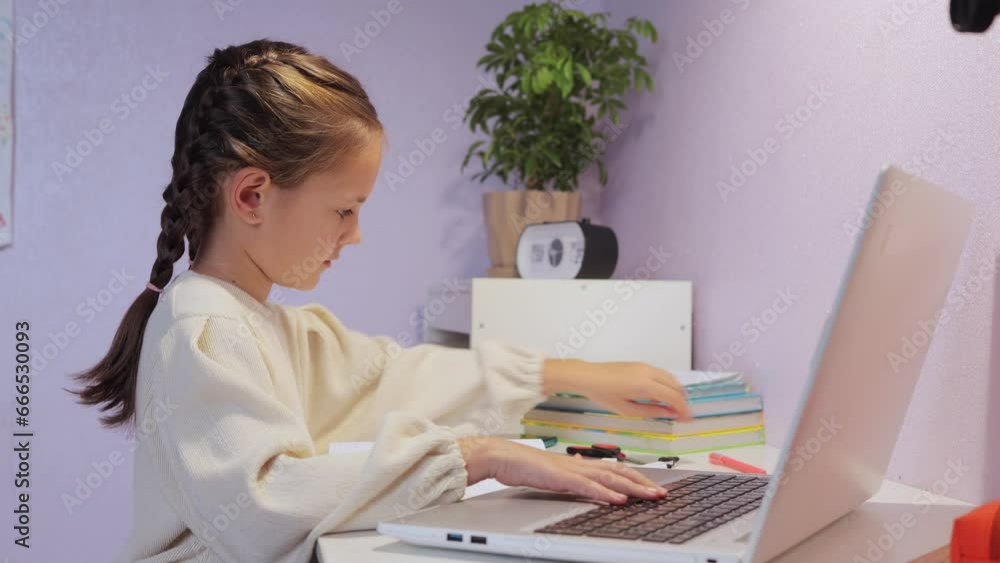 Digital learning tools. Homeschooling options. Child-friendly apps. Distance learning tips. Concentrated little girl with pigtails wearing white shirt sitting at desk in front laptop. Digital learning tools. Homeschooling options. Child-friendly apps. Distance learning tips. Concentrated little girl with pigtails wearing white shirt sitting at desk in front laptop.