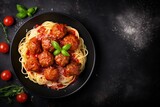 Spaghetti with meatballs and tomato sauce in a black bowl on a dark background Top view with space for text