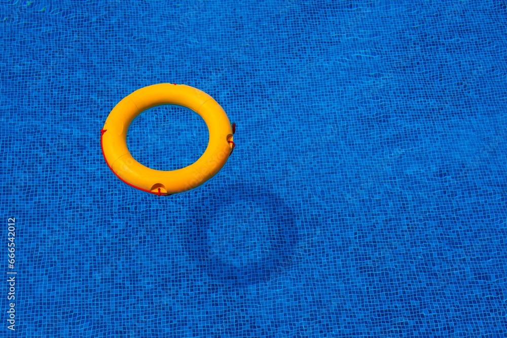 Top view of lifebuoy floating in blue swimming pool, soft focus. Top view of lifebuoy floating in blue swimming pool, soft focus.