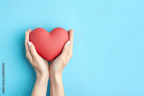 hand holds a heart love shape on a blue background with copy space