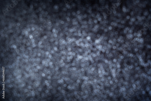 Blurred defocus abstract background or backdrop of black colour with silver bokeh lights used as design element in greeting decoration for holidays celebration. Horizontal image with copy space