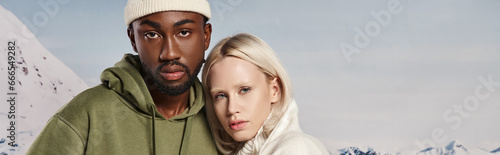 interracial couple posing together in warm jackets with snowy backdrop, winter fashion, banner © LIGHTFIELD STUDIOS