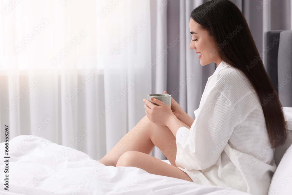 Happy woman with cup of drink on bed at home, space for text. Lazy morning Happy woman with cup of drink on bed at home, space for text. Lazy morning